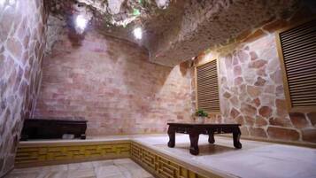 A stone-walled room with a bench, a table, and a window with shutters.