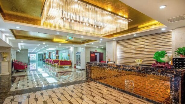 Un vestíbulo de hotel con suelo de mármol, un mostrador de recepción y una araña.