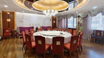 Mesa de jantar redonda com cadeiras vermelhas, um lustre e piso de madeira.