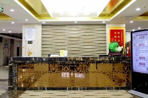 A hotel reception desk with a marble counter, a digital screen, and a red decorative banner. - Xingya Mingdu Hotel (Jinzhong)