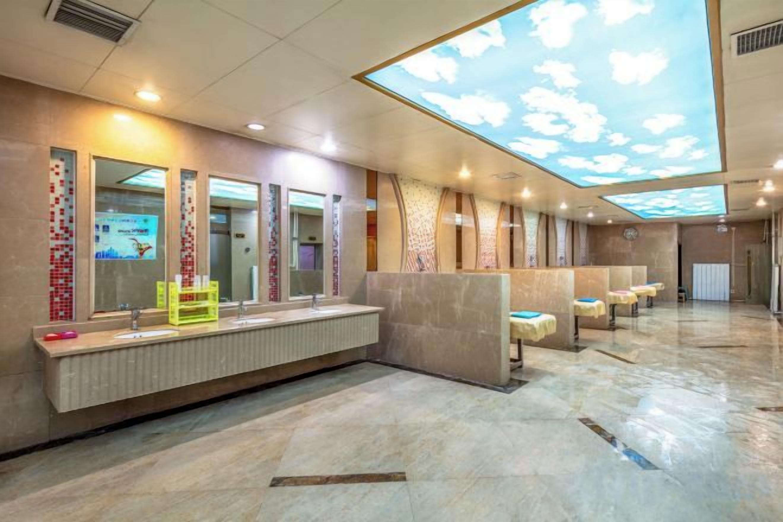 Ein modernes Badezimmer mit Dachfenster, mehreren Waschbecken und einer Sitzbank.