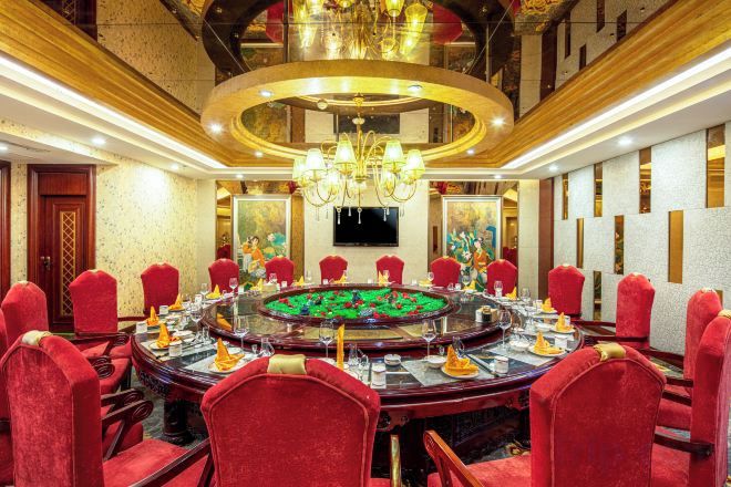 A conference room with a round table, red chairs, and a chandelier.
