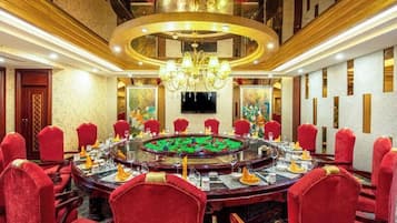 A conference room with a round table, red chairs, and a chandelier.