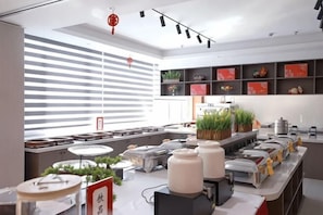 A modern kitchen with a long counter, various kitchen appliances, and potted plants. - Xingya Mingdu Hotel (Jinzhong)