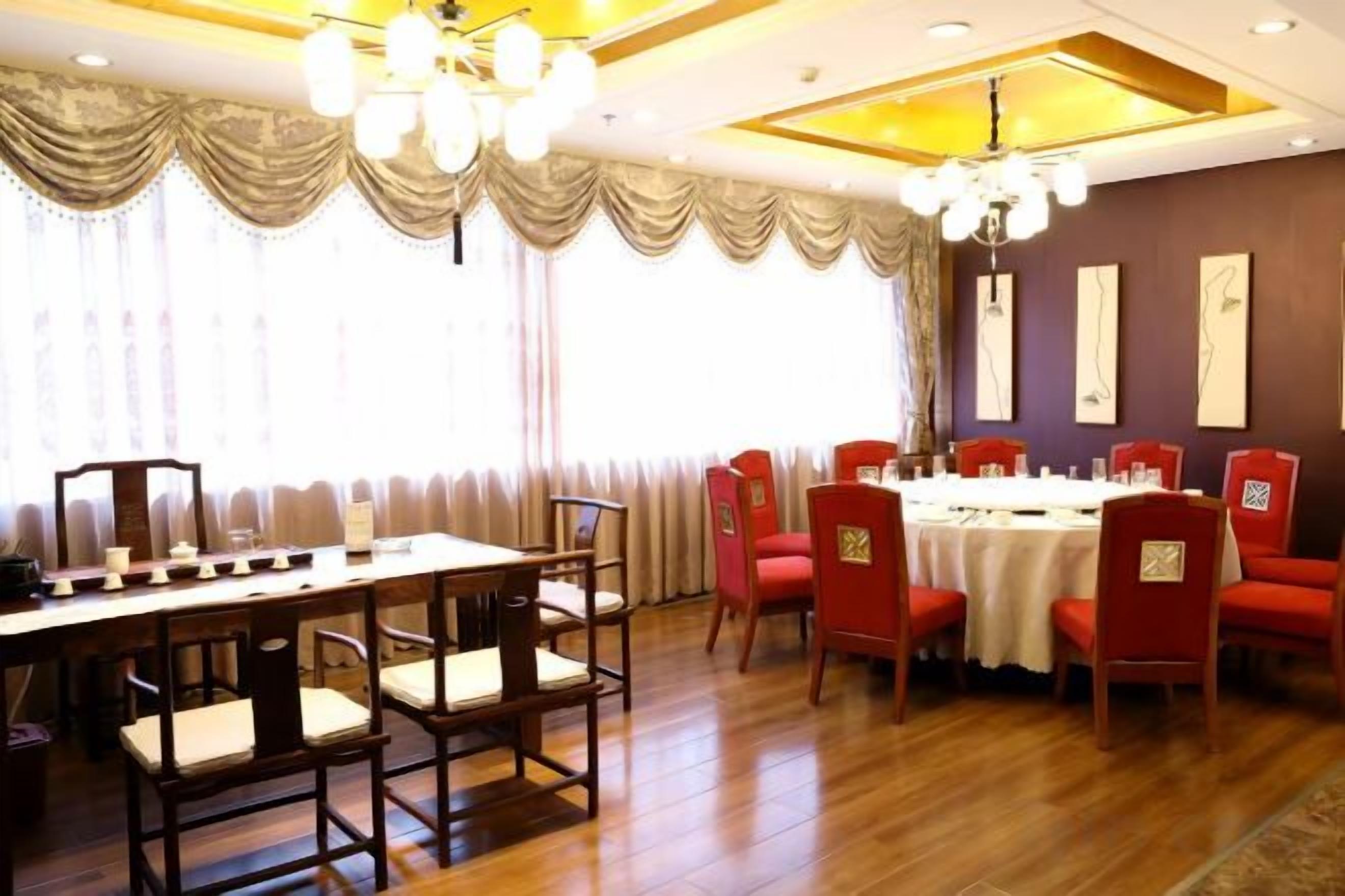A dining area with a long table and chairs, a chandelier, and a view of the outdoors.