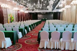 A conference room with rows of tables and chairs, a red carpet, and chandeliers. - Xingya Mingdu Hotel (Jinzhong)