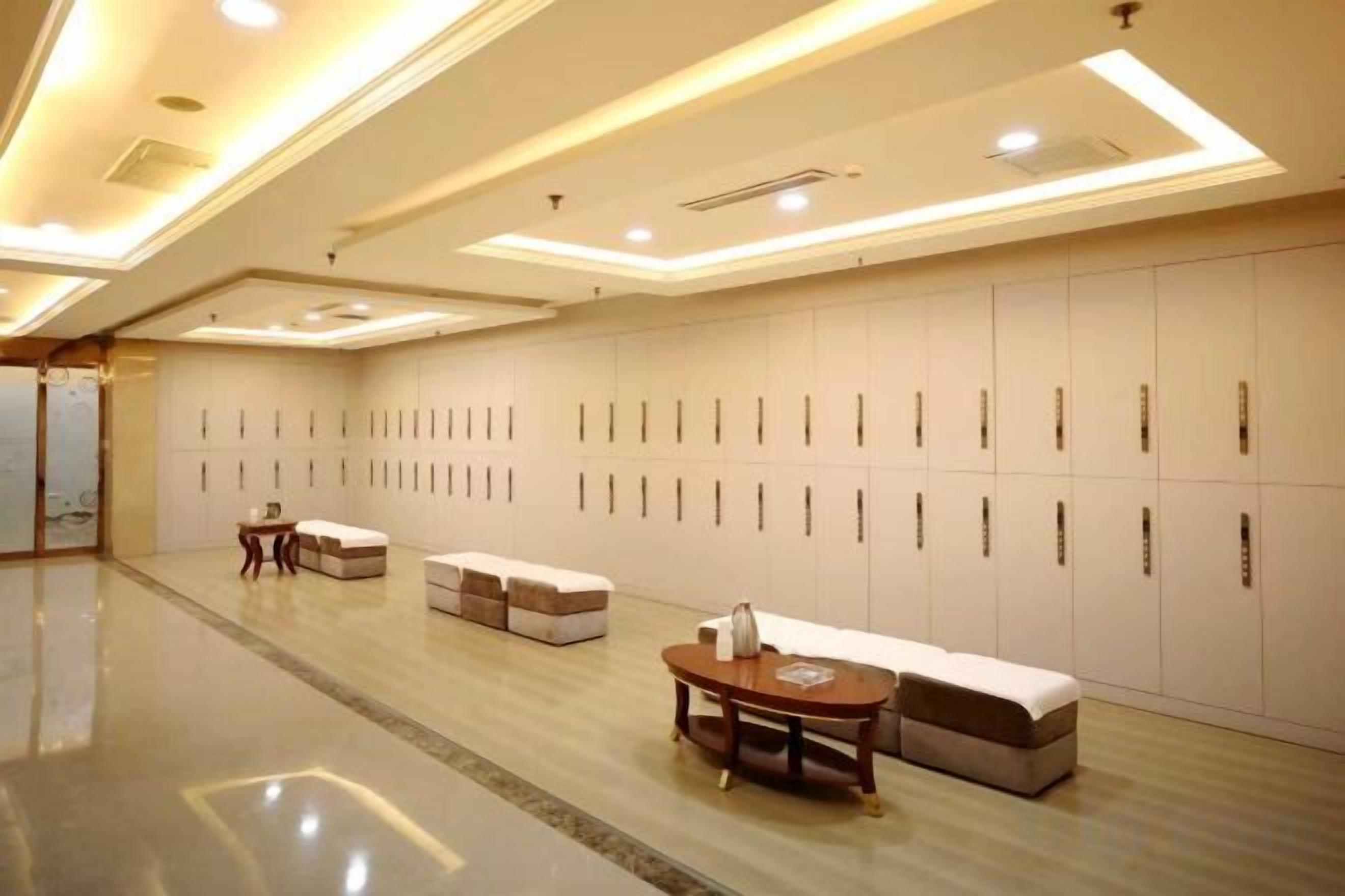 Un hall d’hôtel avec une longue rangée de casiers, un espace détente avec une table ronde et un banc.