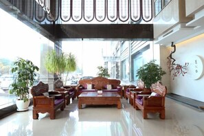 A spacious lobby with a high ceiling, large windows, and a seating area with sofas and chairs. - Xingya Mingdu Hotel (Jinzhong)
