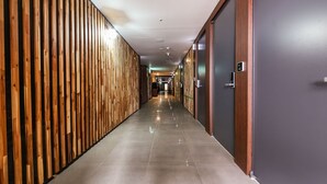 Un pasillo largo y estrecho con paneles de madera a un lado y una puerta oscura al otro.