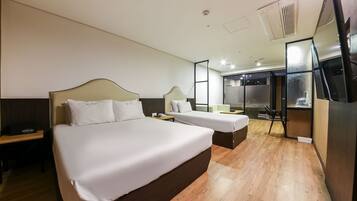 A hotel room with a large bed, a smaller bed, a desk, and a seating area.