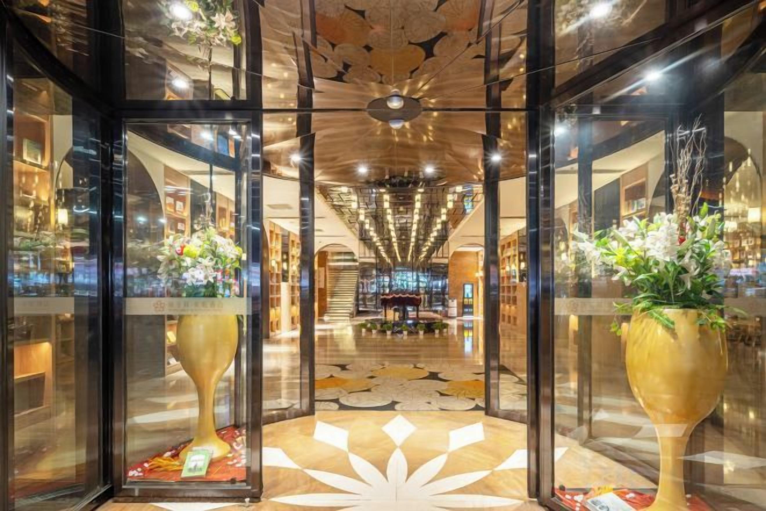 A hotel lobby with a central staircase, large decorative vases, and a patterned floor.