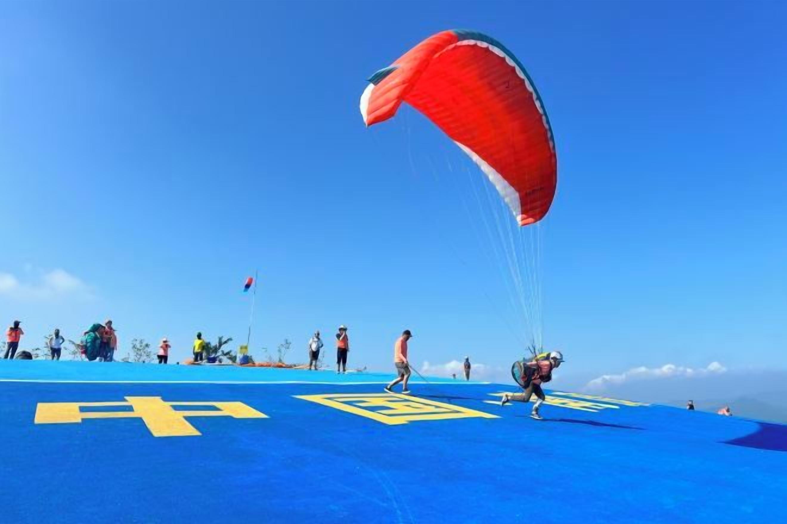 A person preparing to parachute on a blue surface with yellow markings.