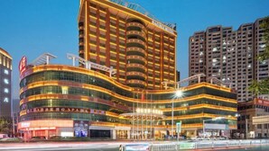 Un hotel a più piani con facciata curva, insegne illuminate e un ingresso ben visibile.