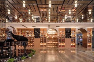 Una biblioteca amplia con estanterías, un piano de cola y un piso de madera pulida.
