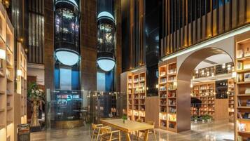 A spacious indoor area with a central table and chairs, surrounded by bookshelves and a large arched structure.