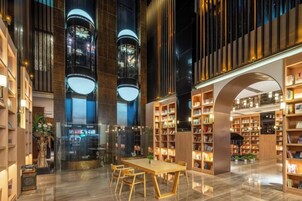Un espacio interior amplio con una mesa central y sillas, rodeado de estanterías y una gran estructura arqueada.