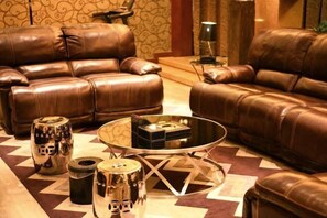 A living room with leather sofas, a glass coffee table, and metallic decorative items. - NEW BAO HUI · HAPPY SLEEP HOTEL (Ganzhou)
