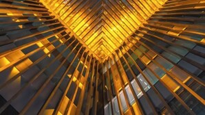 Un edificio moderno con facciata geometrica e un atrio centrale illuminato da luci calde.