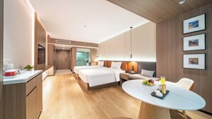 Una moderna camera d'albergo con un letto grande, un tavolo da pranzo, un angolo cottura e un bagno.