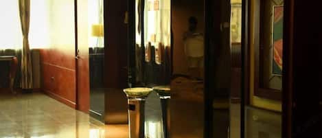 Corridoio di un hotel con pavimento lucido, una reception e una porta in vetro con il cartello del numero.