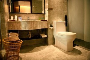 A bathroom with a marble sink, a toilet, a wicker basket, and a mirror. - NEW BAO HUI · HAPPY SLEEP HOTEL (Ganzhou)