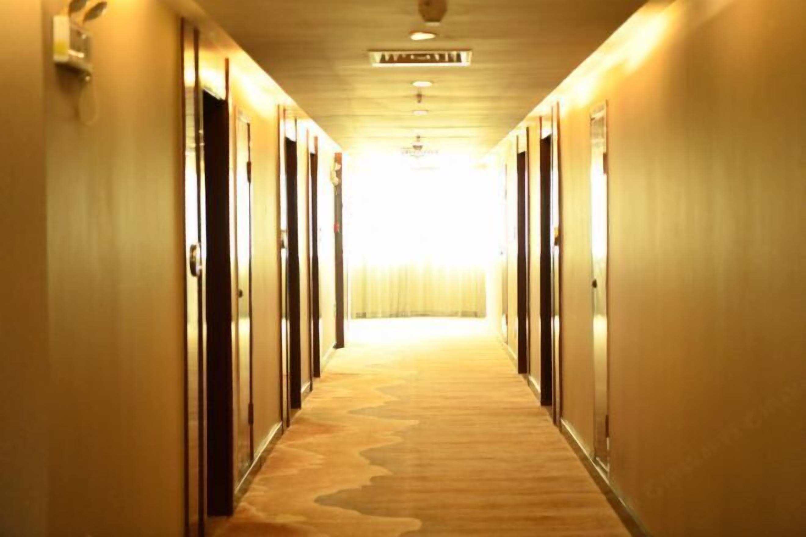 A hotel hallway with doors on both sides leading to rooms.