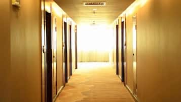 A hotel hallway with doors on both sides leading to rooms.