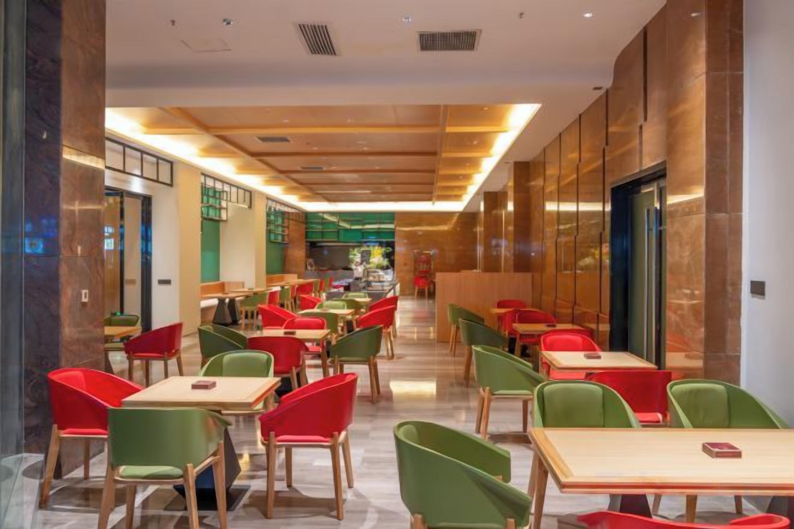 A modern restaurant with multiple tables and chairs, a central walkway, and a view of the dining area.
