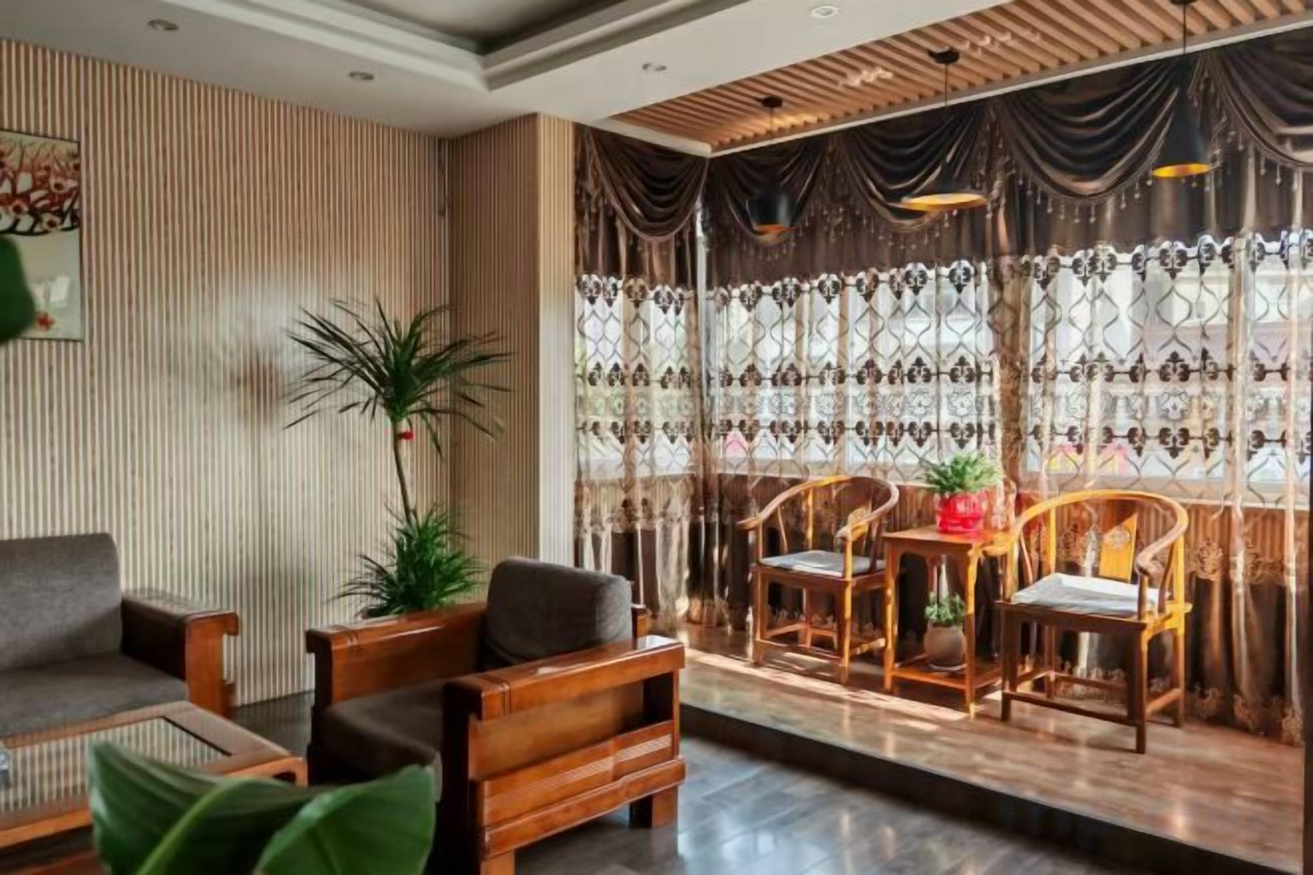 A modern hotel lobby with a seating area, a large window with curtains, and a potted plant.
