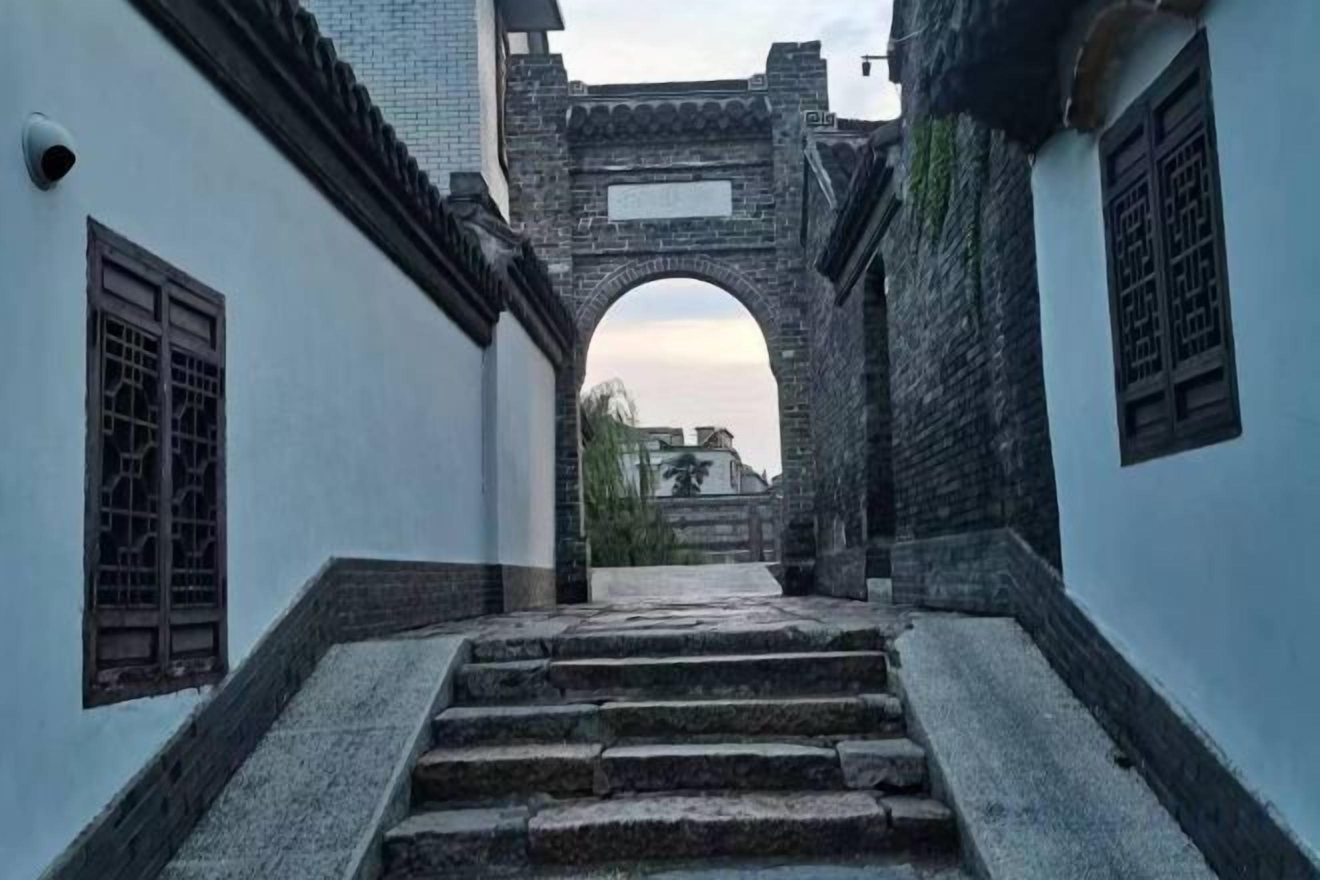 A narrow alleyway with a stone staircase leading to a traditional archway.