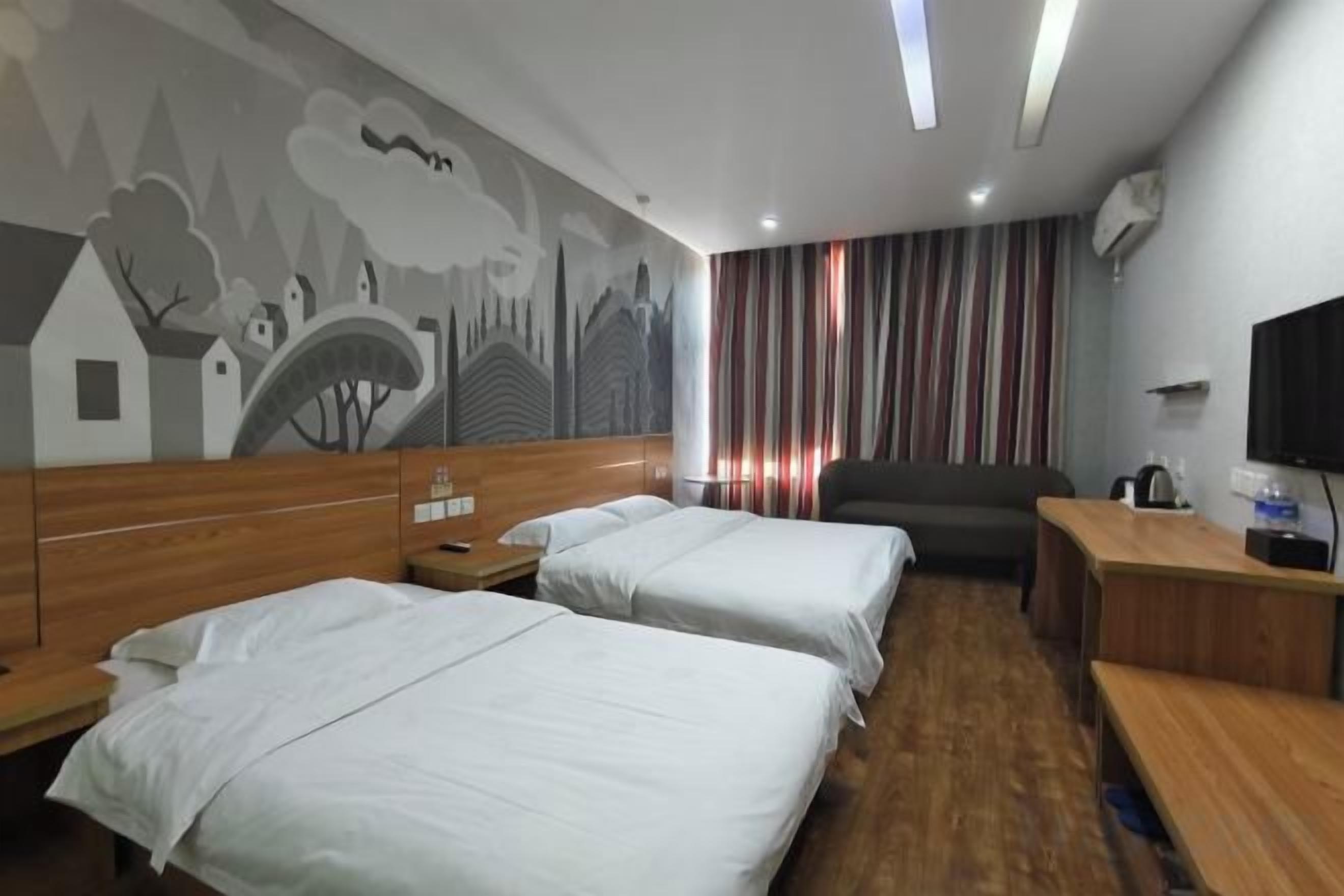 A hotel room with two beds, a desk, a chair, a TV, and a mural on the wall.