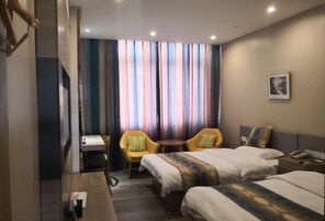Habitación de hotel con dos camas, un escritorio, una silla y una mesita.