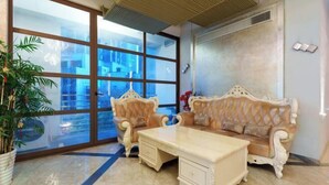 A room with a large window, a sofa, a coffee table, and a potted plant. - Yongcui Hotel (Shenzhen Luohu Shuibei Jewelry City) (Shenzhen)