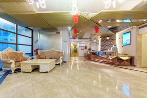 A hotel lobby with a seating area, a reception desk, and a kitchen in the background. - Yongcui Hotel (Shenzhen Luohu Shuibei Jewelry City) (Shenzhen)