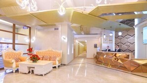 A hotel lobby with a reception desk, two sofas, a coffee table, and a decorative wall. - Yongcui Hotel (Shenzhen Luohu Shuibei Jewelry City) (Shenzhen)