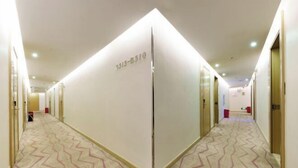 A hotel corridor with a zigzag patterned carpet, a mirrored wall with a number, and doors on both sides. - Yongcui Hotel (Shenzhen Luohu Shuibei Jewelry City) (Shenzhen)