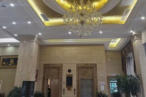 A lobby with a chandelier, marble walls, and elevators. - Sunjiang Hotel (Quanzhou)