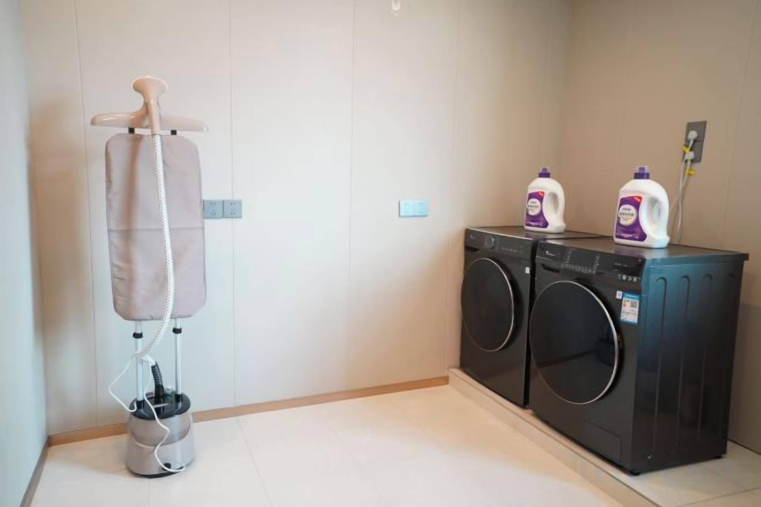 A laundry area with a washing machine, dryer, and a hanging clothes rack.