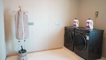 A laundry area with a washing machine, dryer, and a hanging clothes rack.