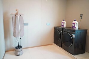 A laundry area with a washing machine, dryer, and a hanging clothes rack. - Sunjiang Hotel (Quanzhou)