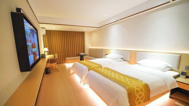 A hotel room with a large bed, a desk, a chair, a TV, and a lamp. - Sunjiang Hotel (Quanzhou)