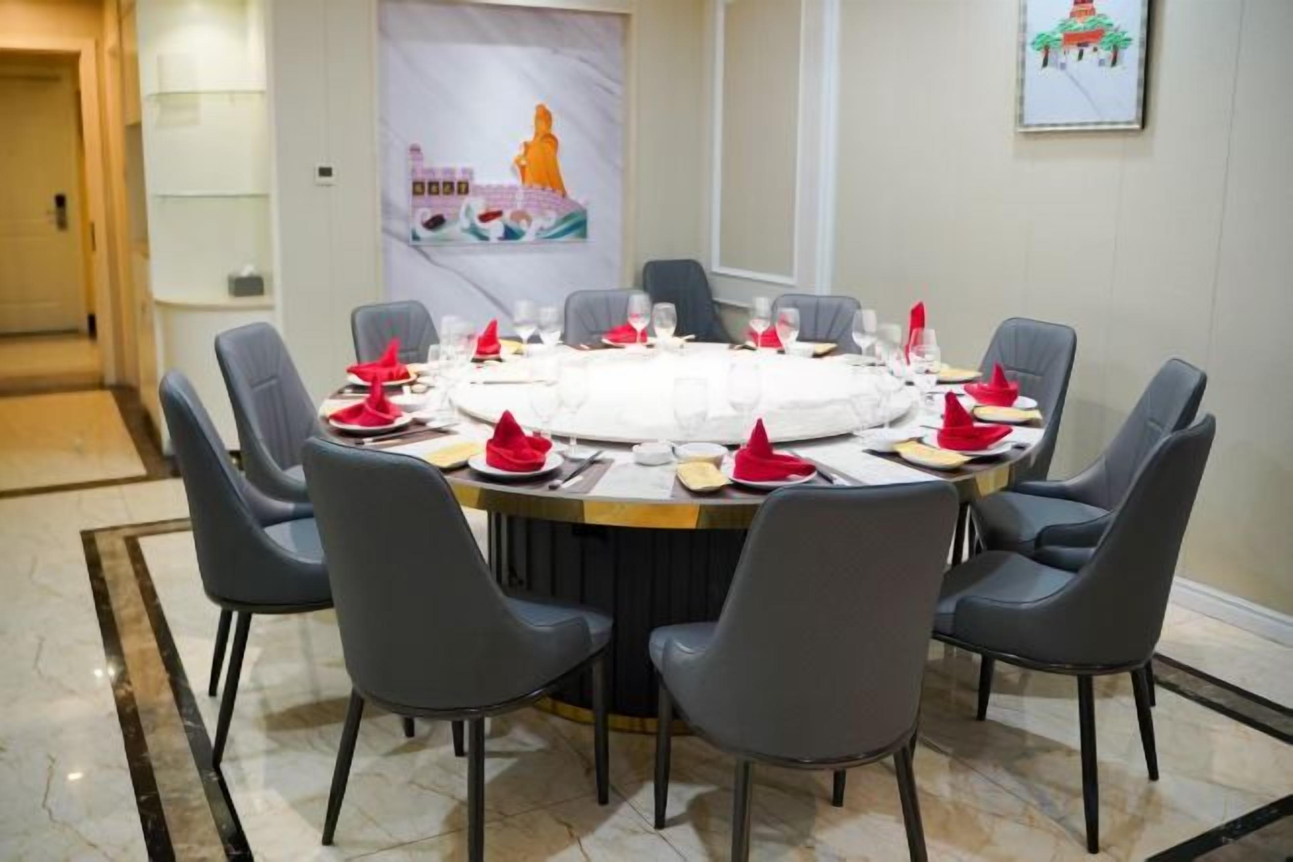 A round table set for a meal with chairs around it.