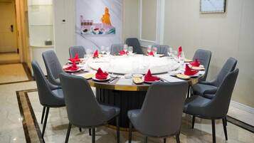 A round table set for a meal with chairs around it.