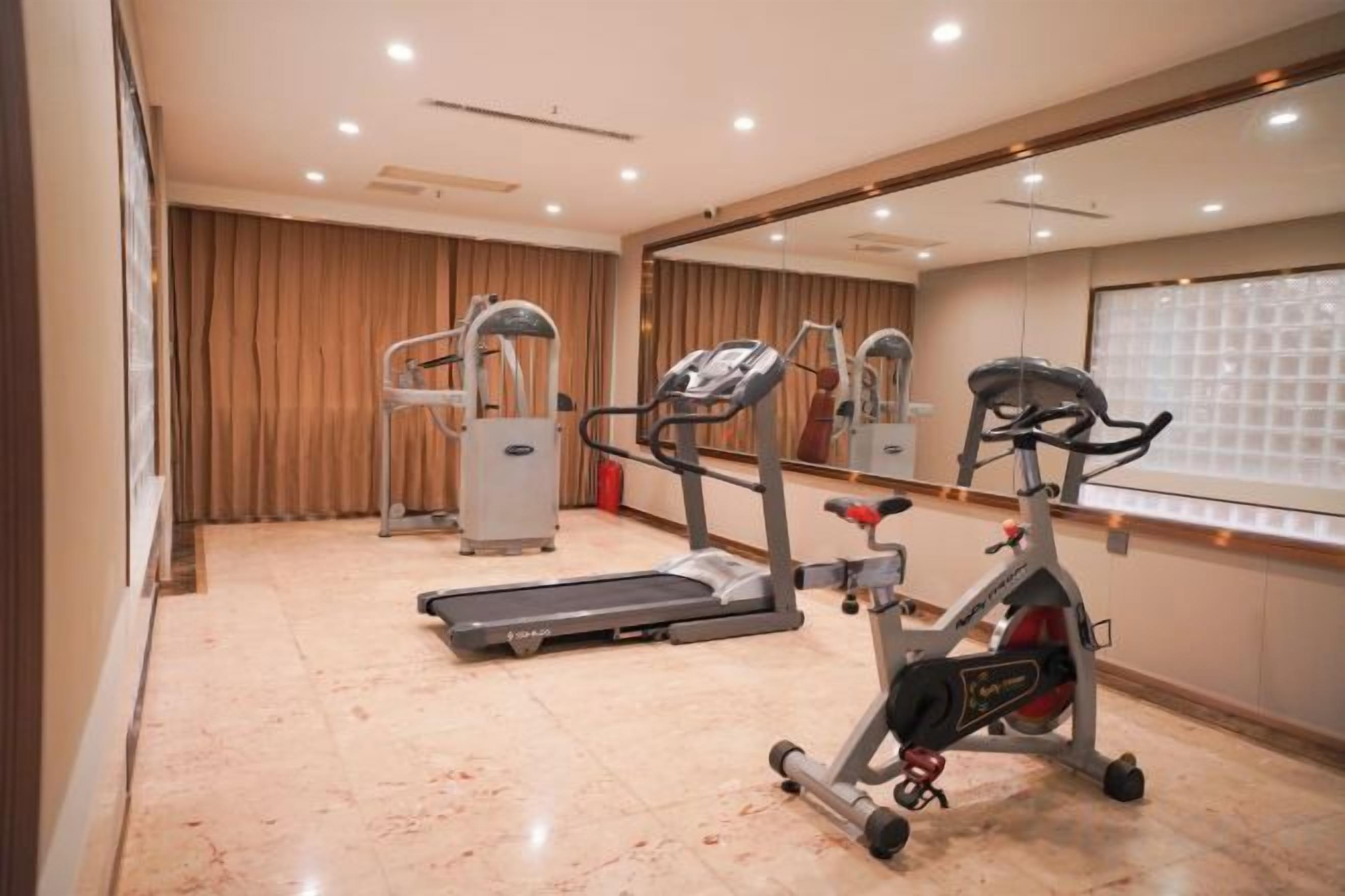 Un gimnasio con cintas de correr, elípticas y una bicicleta estática.