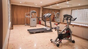 A gym with exercise equipment, a mirrored wall, and a large window. - Sunjiang Hotel (Quanzhou)