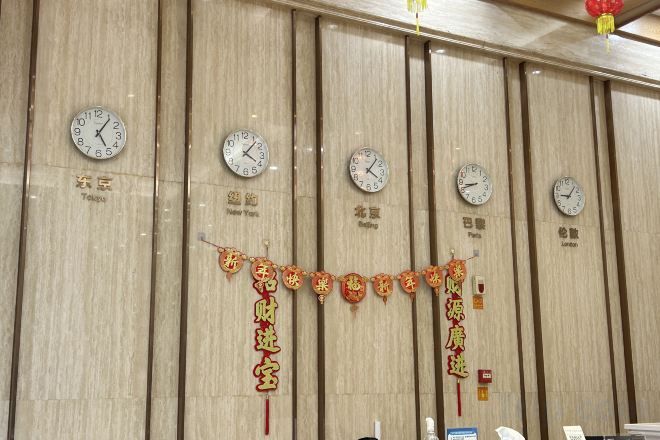 Una pared con relojes y caracteres chinos, mostrando diferentes husos horarios.