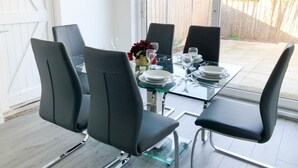 Un comedor con una mesa de vidrio y cuatro sillas negras.