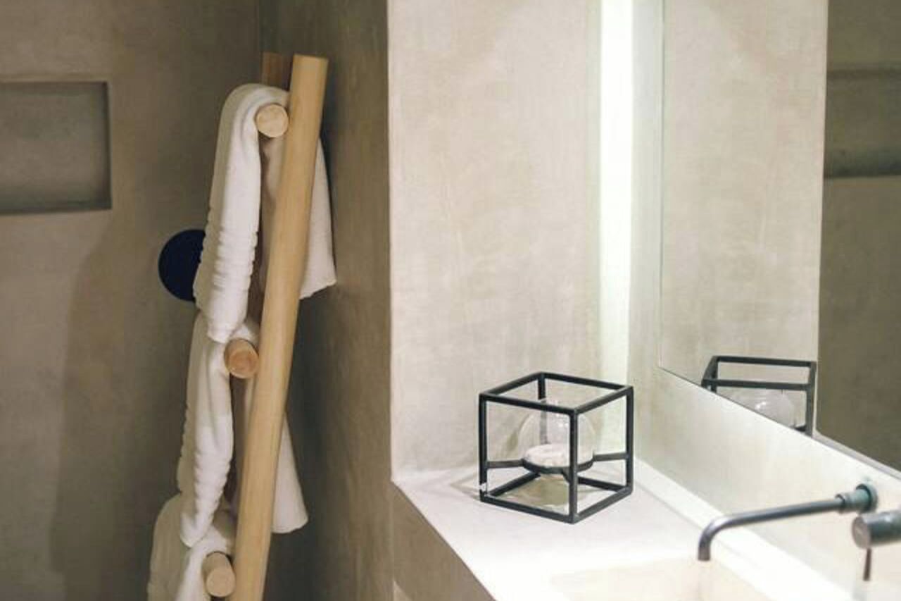 A bathroom with a white sink, a mirror, a towel rack, and a glass cube on the counter.