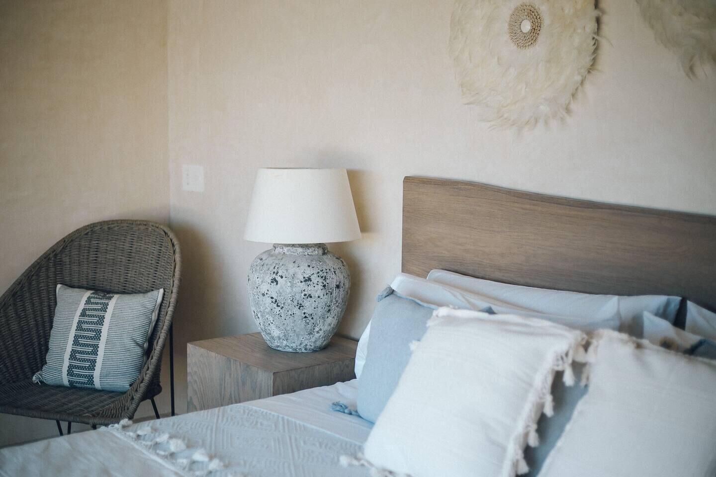 A bedroom with a bed, a chair, a nightstand, and a lamp.