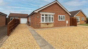 A single-story brick house with a garage, a gravel driveway, and a wooden fence. - Cedar Drive, Holbeach - 1 to 4 - Self Catering (Spalding)